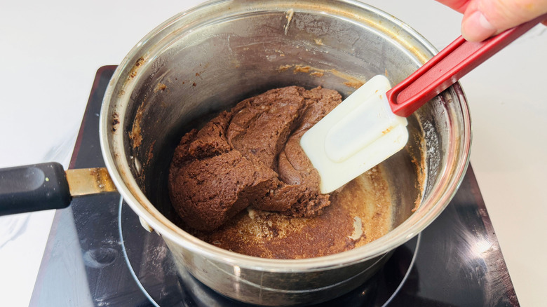 Spatula mixing chocolate dough in saucepan