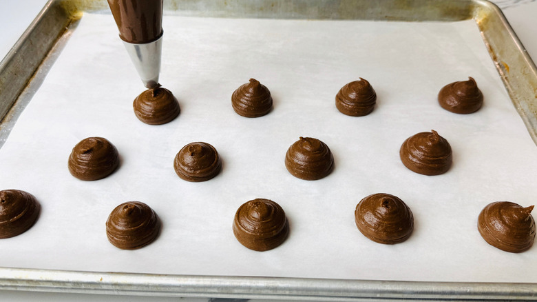 Chocolate batter swirls piped onto baking sheet