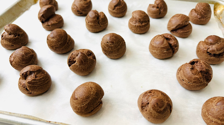 Chocolate cream puff pastries on baking sheet