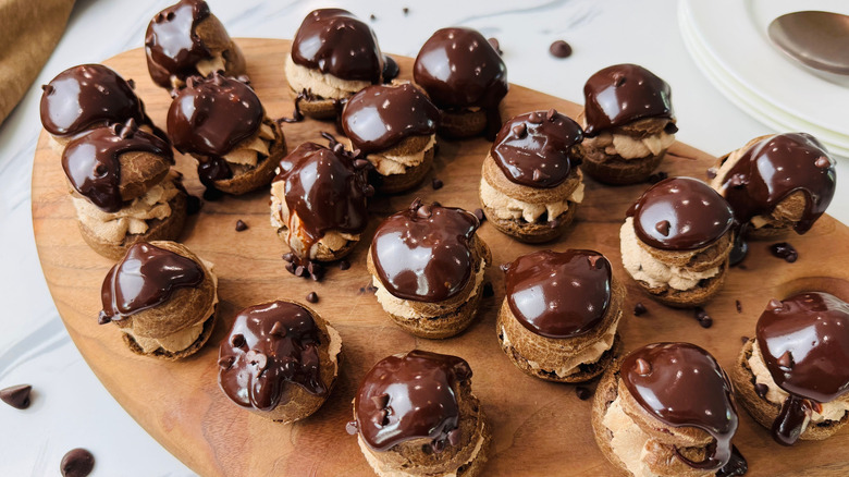 Triple chocolate cream puffs on wooden board