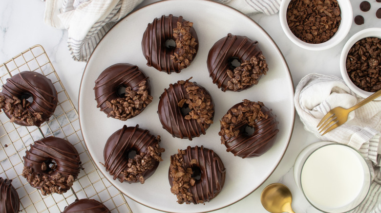 Chocolate donuts with cereal toppings on plate and wire rack