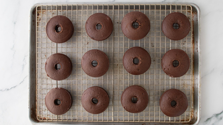 Baked chocolate donuts on wire rack over baking sheet