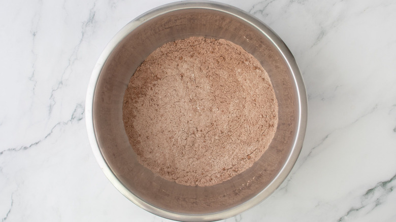 Aerial view of cocoa powder and flour mixture in bowl on marble surface
