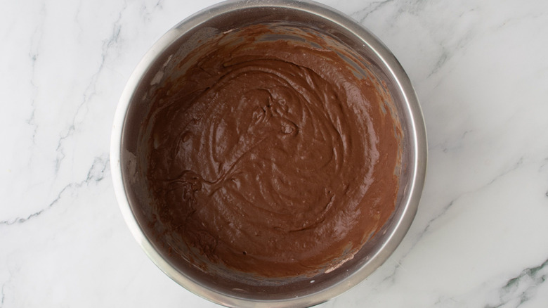 Chocolate donut cake batter in bowl on marble surface