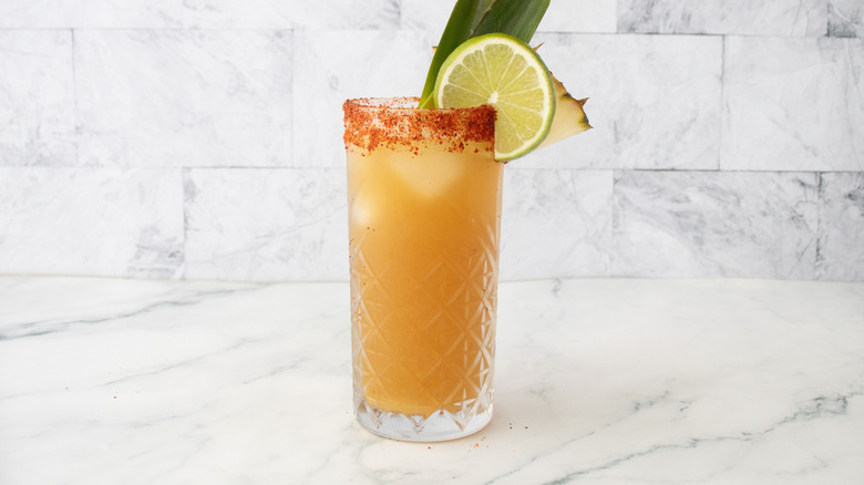 Tropical rum shandy in glass with garnishes and Tajín rim