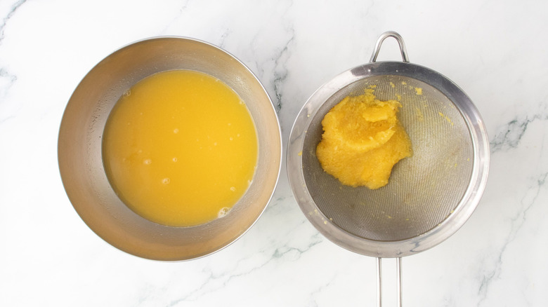 Tropical fruit juice in bowl next to pulp in strainer