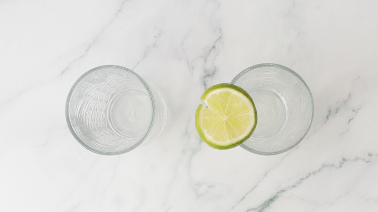 Two glasses with lime wedge on top of one