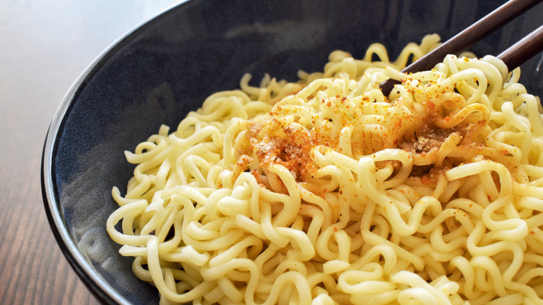 Instant ramen noodles in a bowl with seasonings sprinkled on