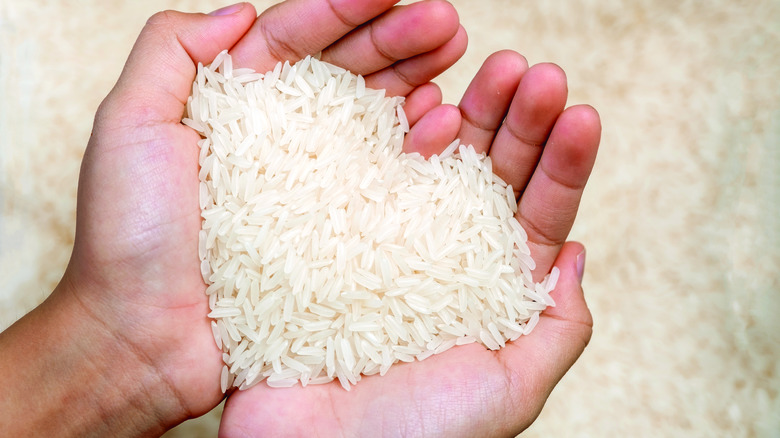 a pair of hands holding uncooked rice in heart shape