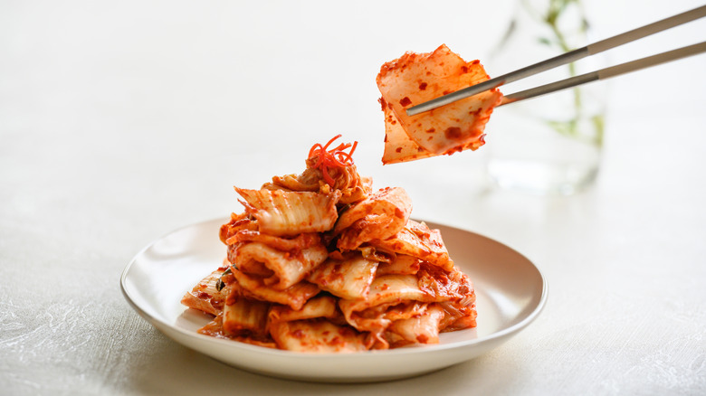 Kimchi on a plate and held by chopsticks