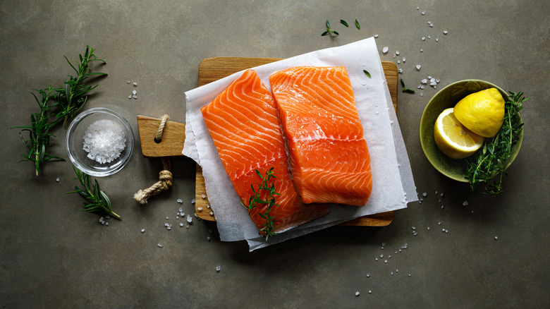 Raw salmon fillets on a napkin along with lemon and salt on either side