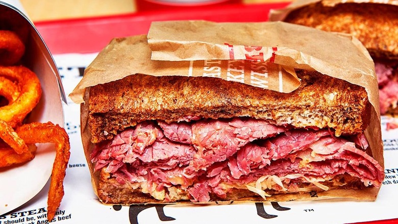 Close-up of half a wrapped Arby's Reuben next to curly fries