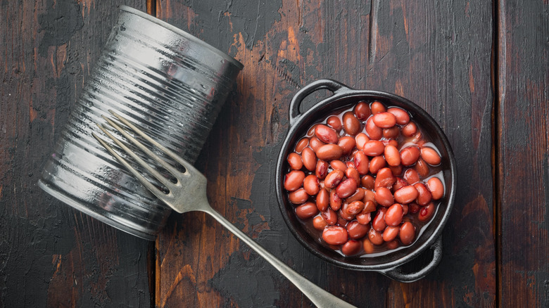 A can with a fork next to a bowl of beans
