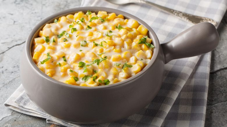 Creamed corn in a bowl, topped with herbs.