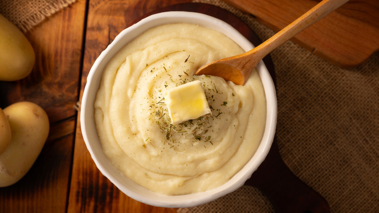 A bowl of mashed potatoes on a wooden board.