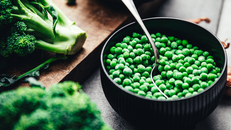 A bowl of green peas on a kitchen counter.