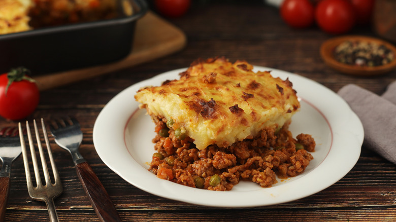 A piece of shepherd's pie on a plate on a wooden table.