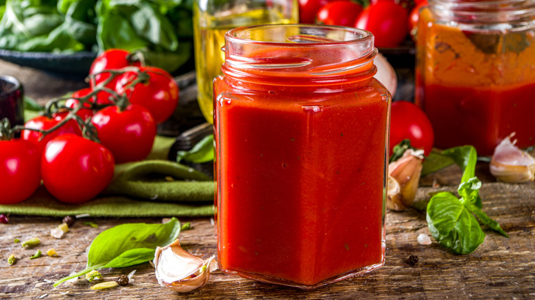 jar of tomato sauce with ingredients around it