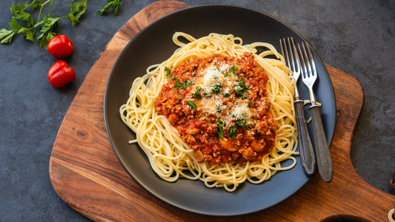 A plate of pasta with sauce on top, two forks on the side