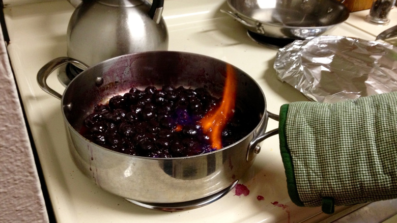 person flambeing cherries on an electric stovetop