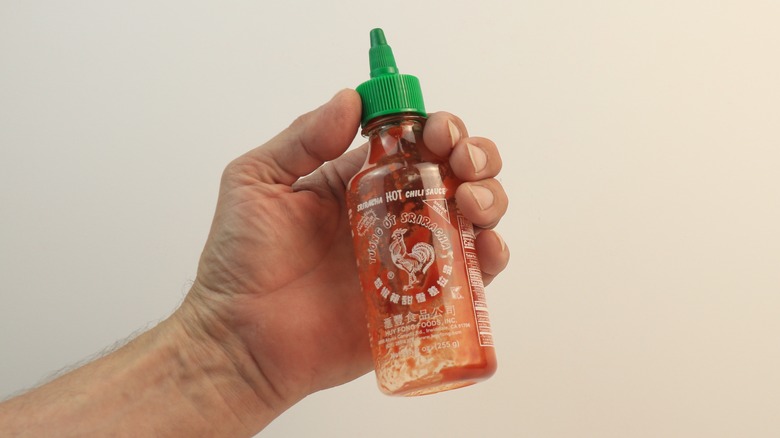 Person holding an empty bottle of sriracha