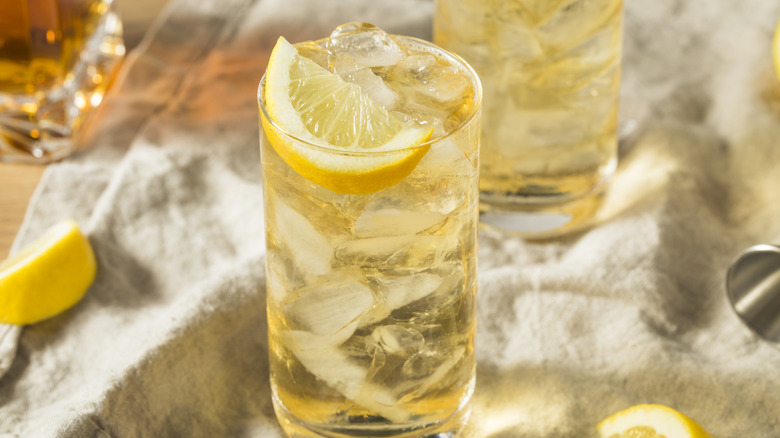 A 7 and 7 cocktail in a highball glass garnished with a lemon