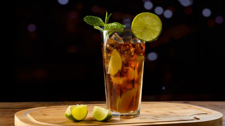 A Cuba libre garnished with lemon, lime, and mint