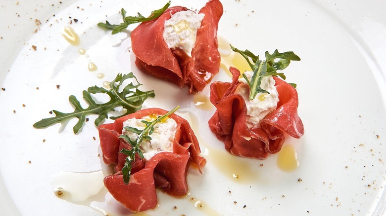 Baked prosciutto cups with a creamy cheese filling topped with honey and fresh arugula