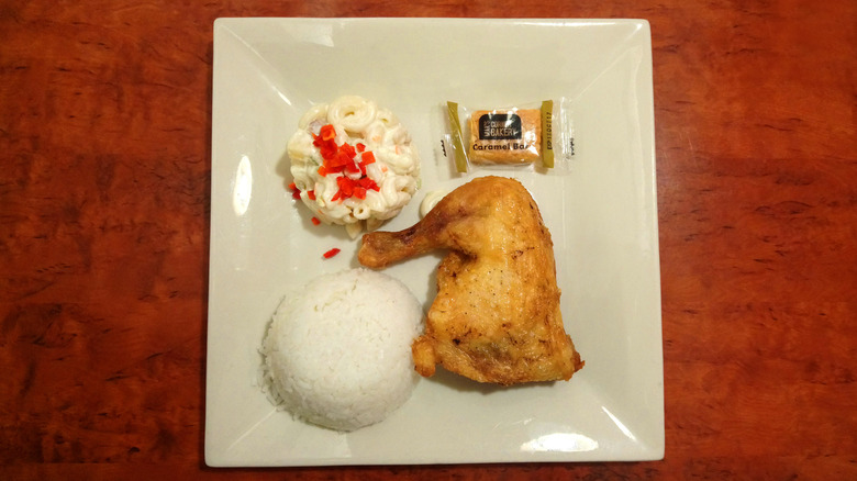 A fried chicken meal from Max's in the Philippines, showing a fried chicken leg, white rice, macaroni salad, and a caramel bar