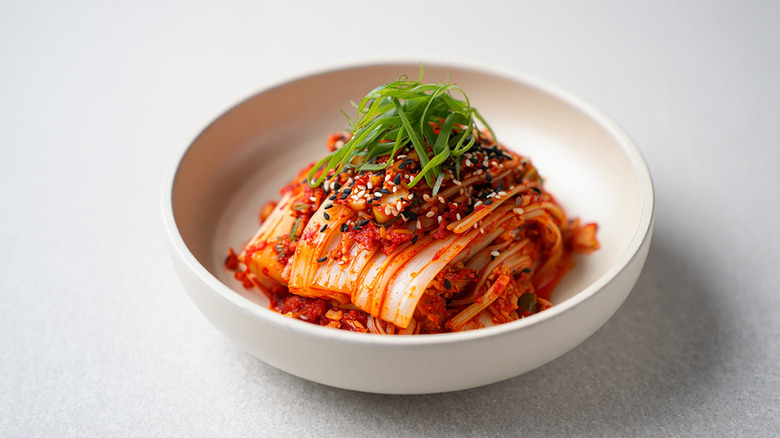 a bowl of napa cabbage kimchi topped with sliced scallions