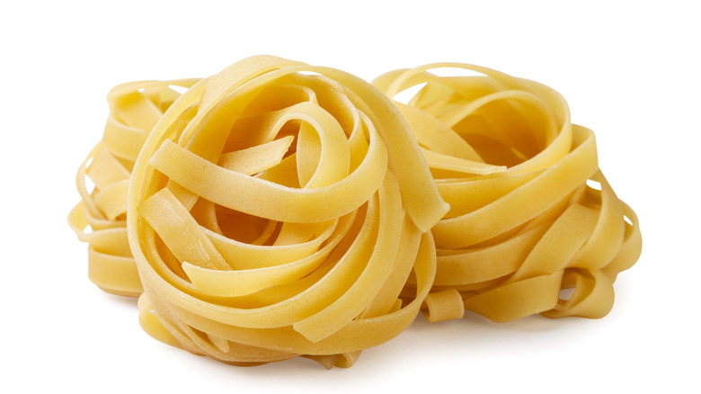 a pile of fettuccine pasta bundles on an isolated white background