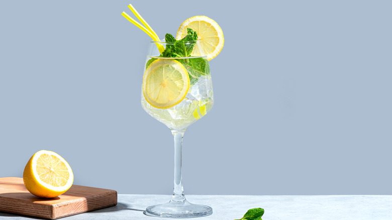 A Hugo spritz with sliced lemon, mint, and a yellow straw.