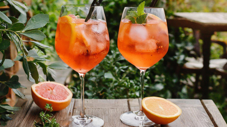 Two Ramazzotti spritz in large wine glasses behind a floral garden background