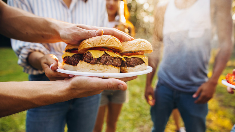 Person carrying burgers on a plate