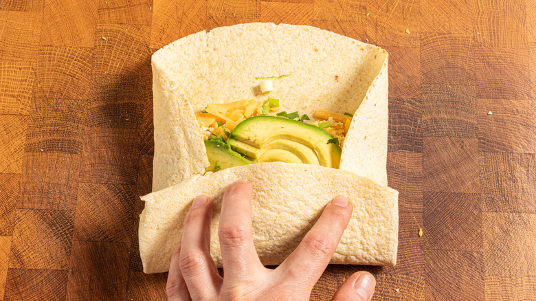 hand rolling breakfast burrito