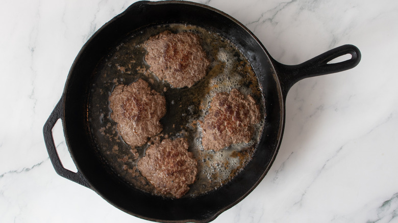 smash burgers cooking in skillet