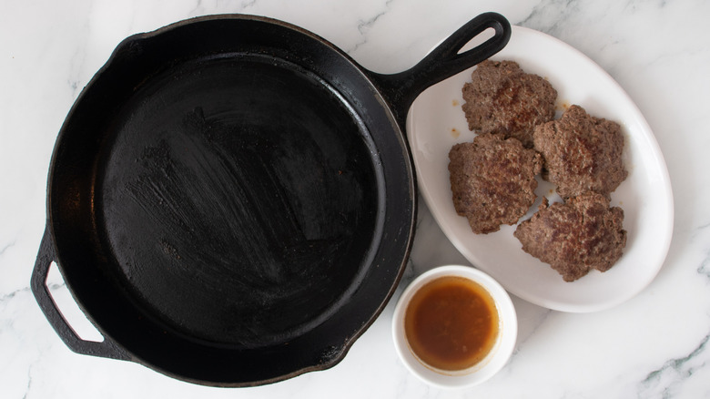 cooked burgers next to an empty skillet