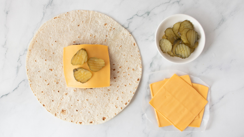burger patty cheese and pickles on tortilla