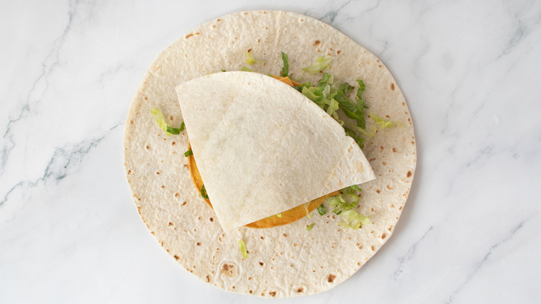 slice of flour tortilla on top of crunch wrap toppings