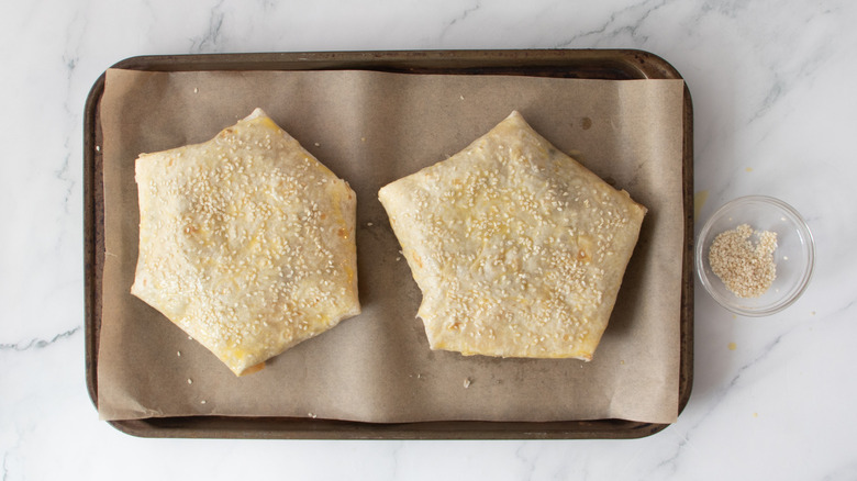 crunch wraps on baking sheet topped with sesame seeds