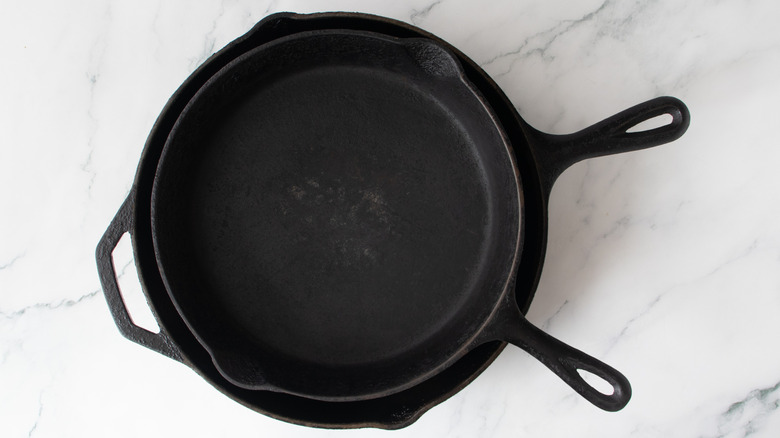 skillet pressing down burgers as they cook