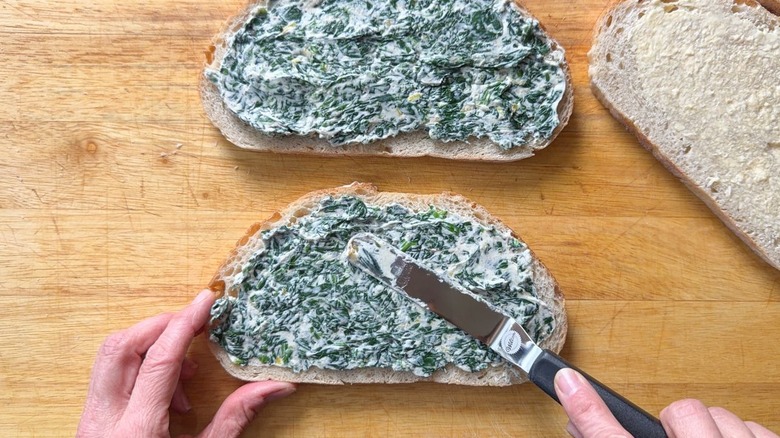 Spreading whipped ricotta and spinach on sourdough bread for grilled cheese