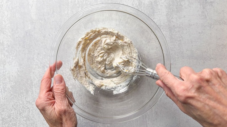Using whisk to whip ricotta and seasonings in glass bowl