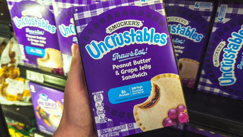 Person holding a box of Smuckers Uncrustable PB&J sandwiches