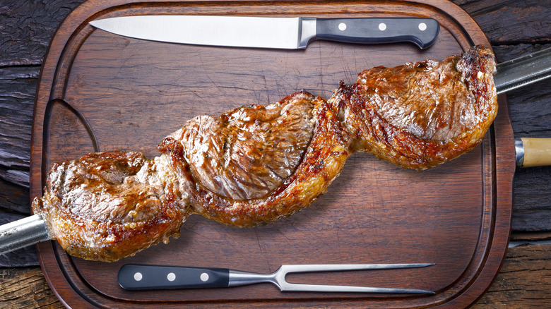 Grilled picanha steak on skewers served on a wooden cutting board