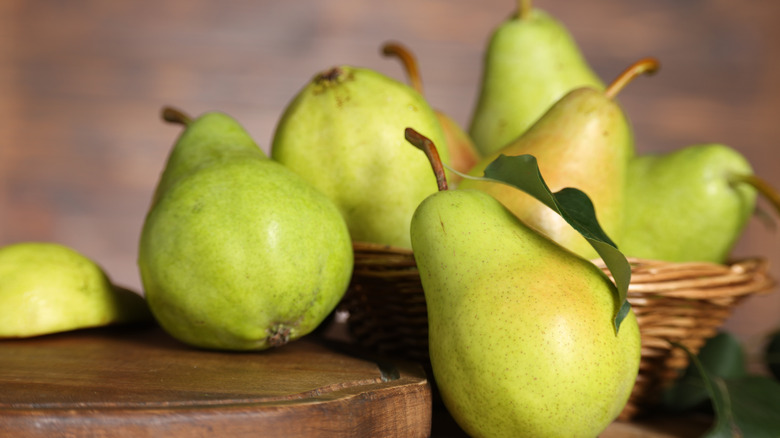 Green pears sit atop a wooden table.