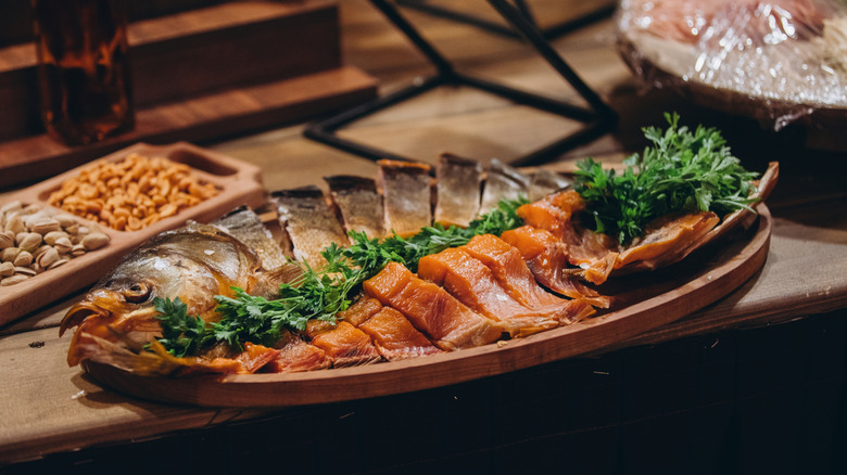 Fish laid out on a platter with greens plus nuts in a dish on the side