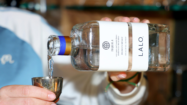 A person pouring a shot of LALO tequila