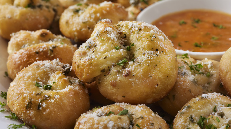 Garlic knots are shown with dipping sauce in the background.