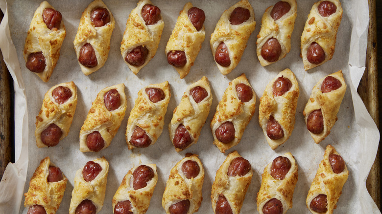 A tray is filled with rows of mini pigs in a blanket.